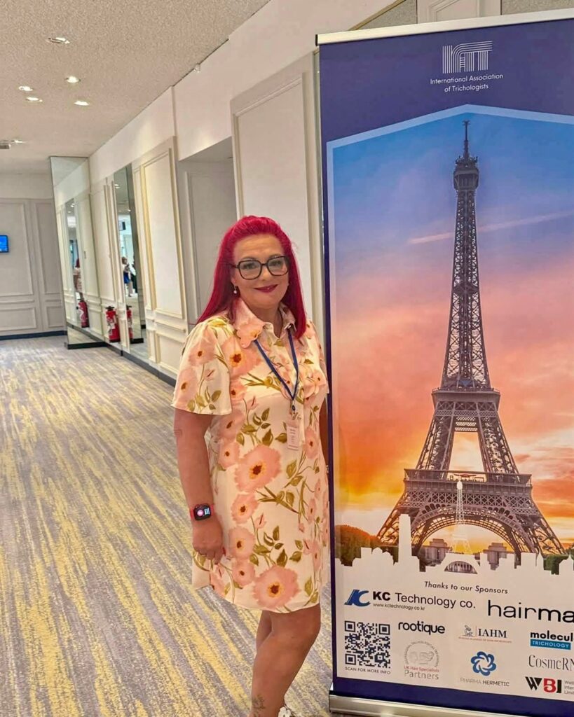 Dr Teresa Wood beside the International Association of Trichologists banner at the 2026 World Trichology Conference in Paris